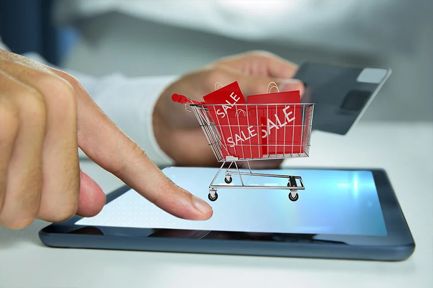 Shopping trolley bearing SALE cards, on top of a tablet screen